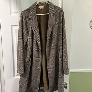 Plaid blazer, pockets, no button. Goes past butt